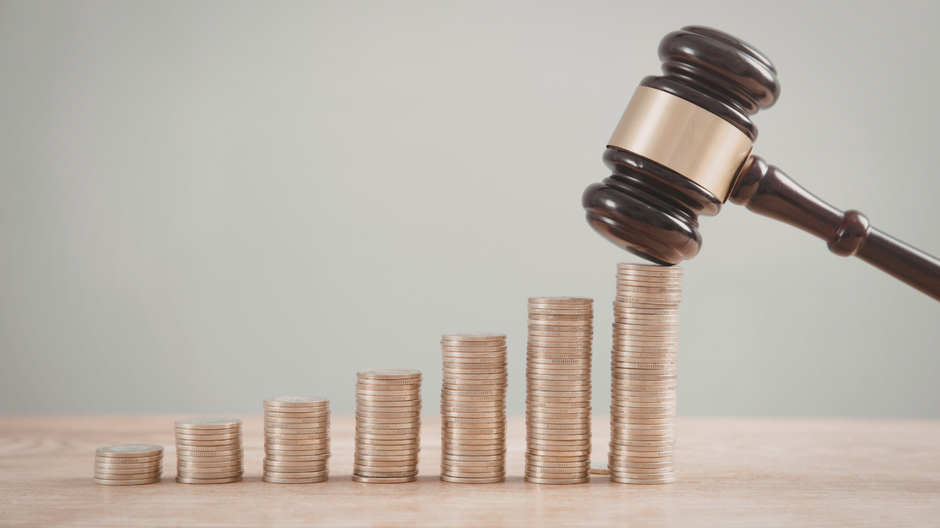 Marteau de juge frappant près de piles de pièces symbolisant le recouvrement de dettes et la justice financière.